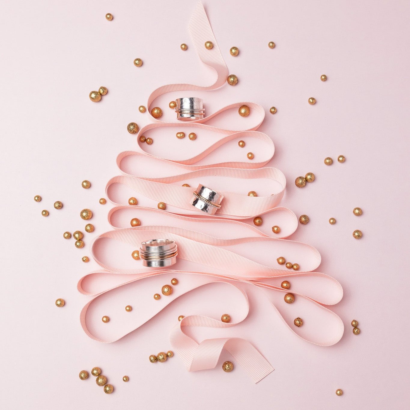 pink decorative ribbon in the shape of a christmas tree with gold balls and three spinner rings