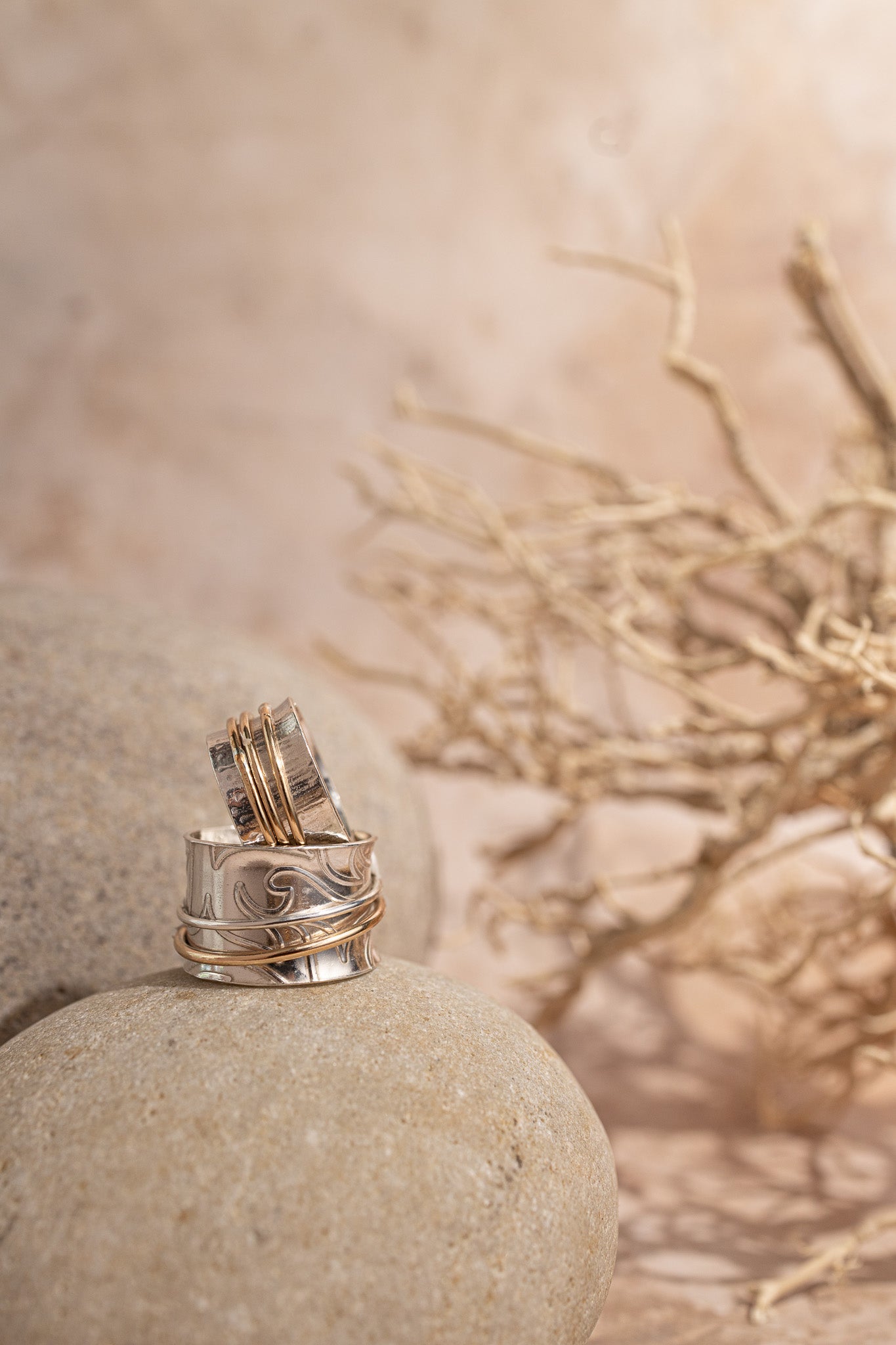 two spinner rings standing on a sandstone with a twig in the background