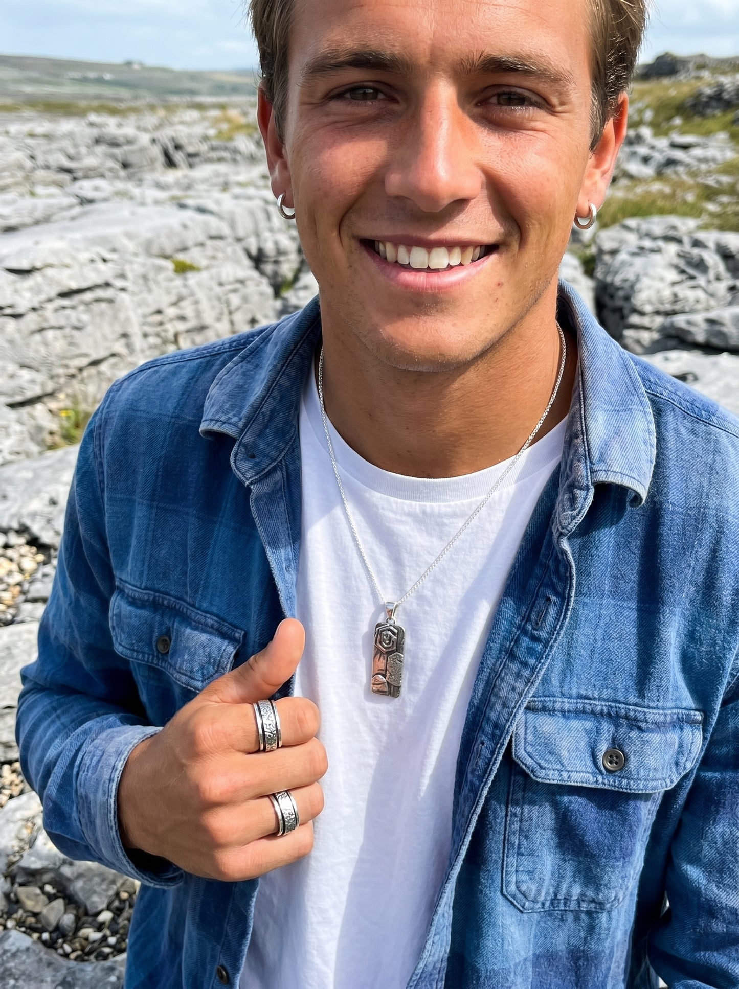 Man giving a thumbs up outdoors with rocky landscape in the background