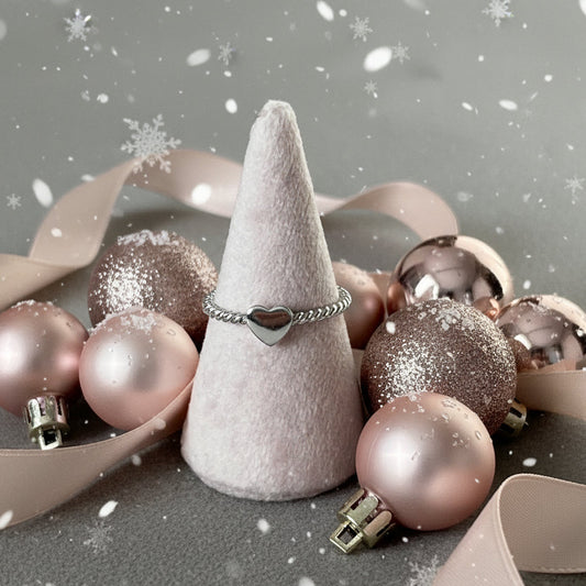Silver ring with a heart design on a gray surface