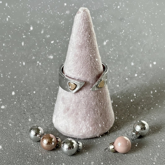 Silver ring with heart-shaped stones on a cone-shaped gray stand.