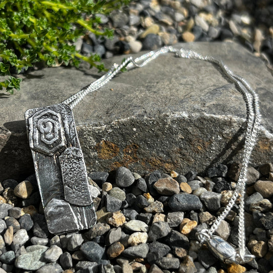Silver necklace with a pendant on a stone surface