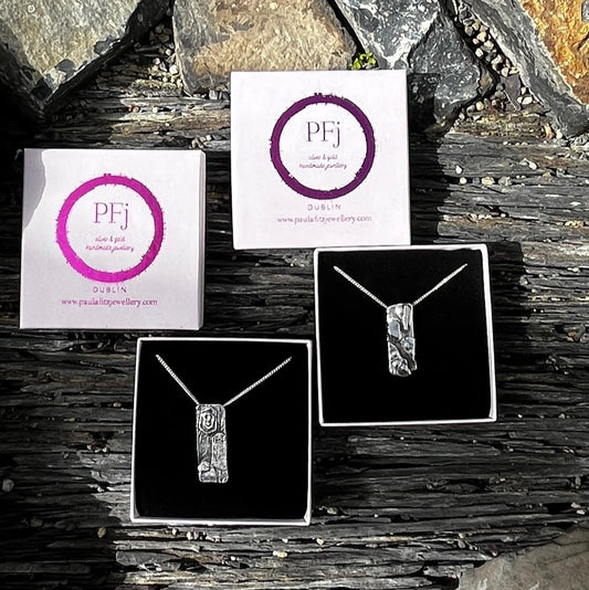 Jewelry display with necklaces and branded cards on a stone surface