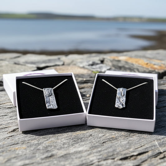 Jewellery display with necklaces and branded cards on a stone surface