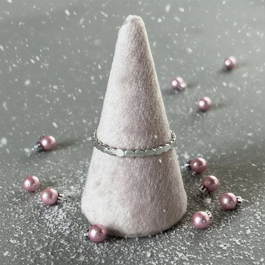 Silver ring on a cone-shaped felt stand against a gray background