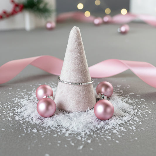Decorative cone with pink ornaments on a gray surface with blurred lights in the background