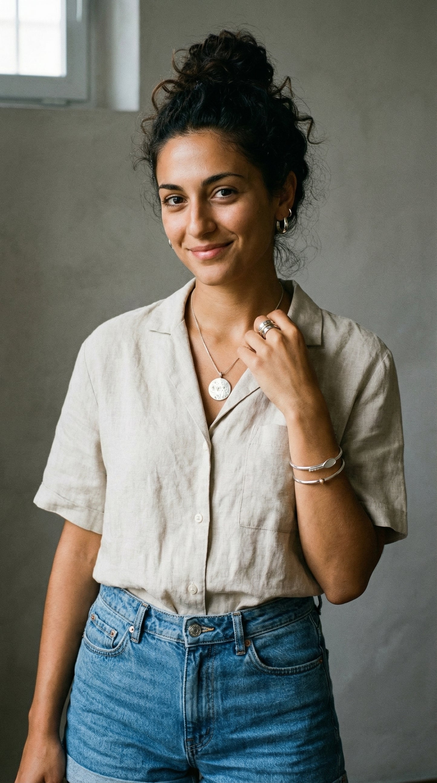 Woman wearing a beige shirt and blue jeans against a plain background