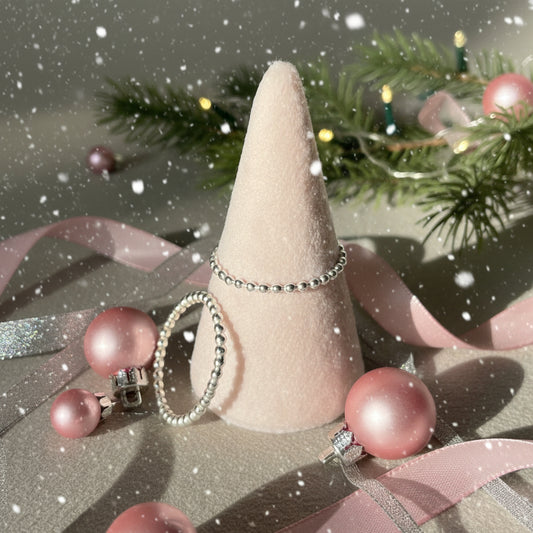 Two silver rings on a cone-shaped jewelry stand against a neutral background