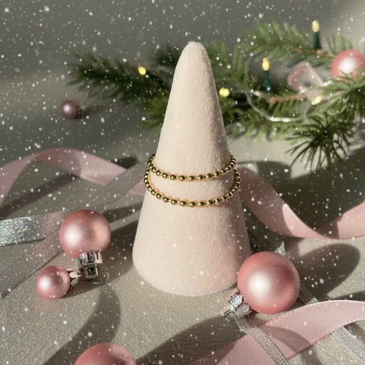 Two silver rings on a cone-shaped jewelry stand against a neutral background