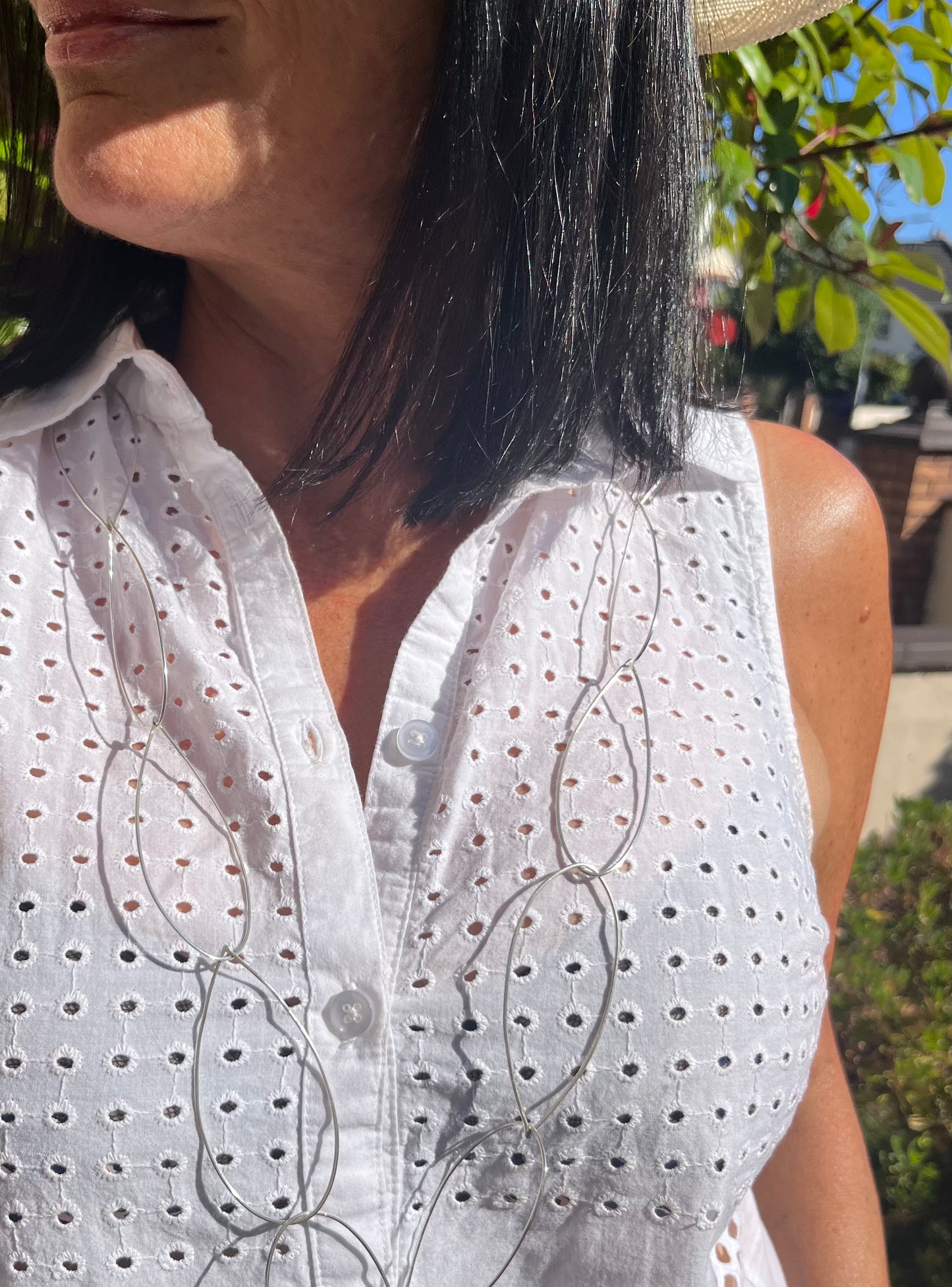 Maker Paula Fitz wearing the cascade necklace white blouse black hair