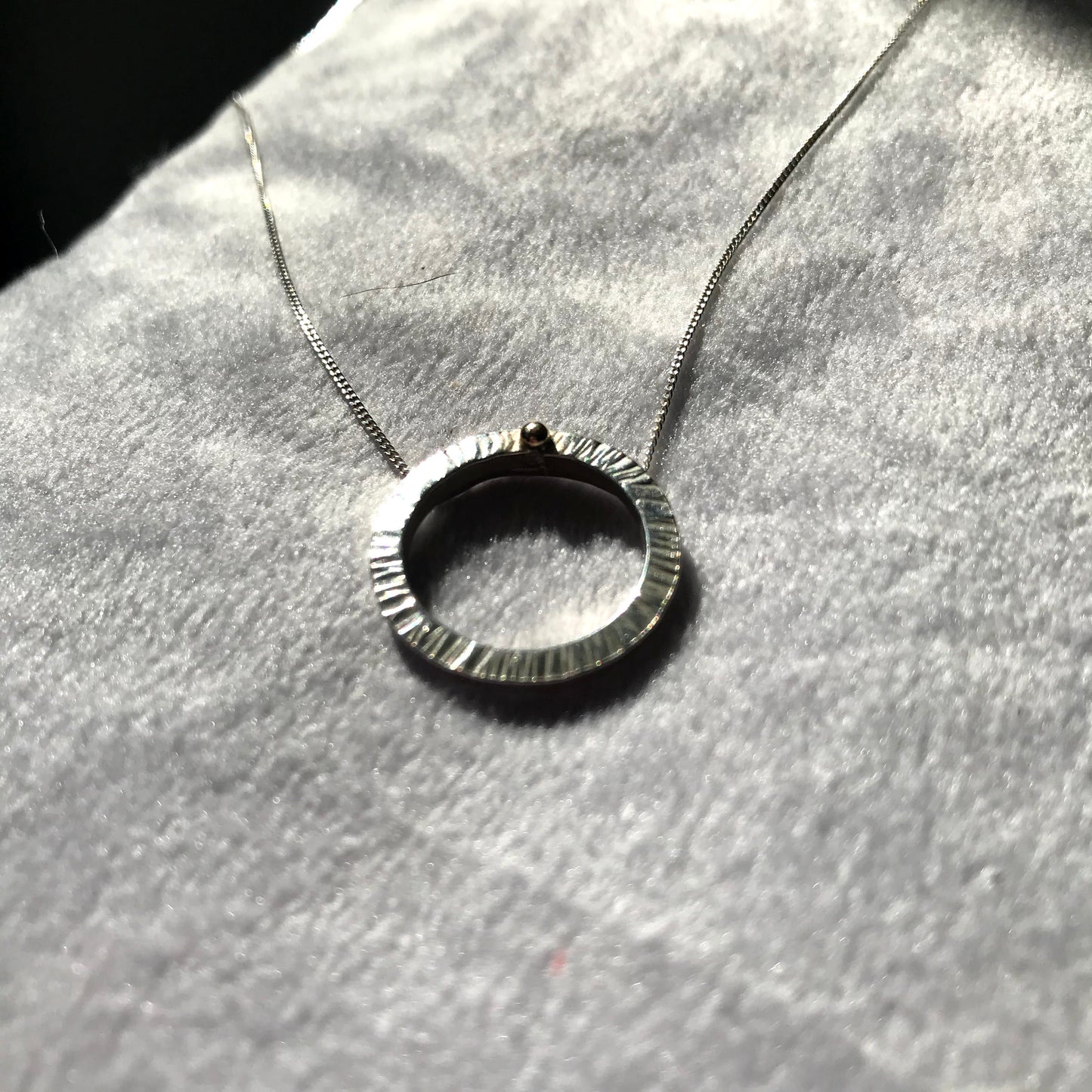 Handmade sterling silver 16mm diameter circle - hammered finish to represent rays of the sun hence the name 'Rise' - this little pendant is suspended on a sterling silver diamond cut curb chain 40cm or 45cm length. The piece is complete with a ball of 9ct gold so you can Rise with gold.