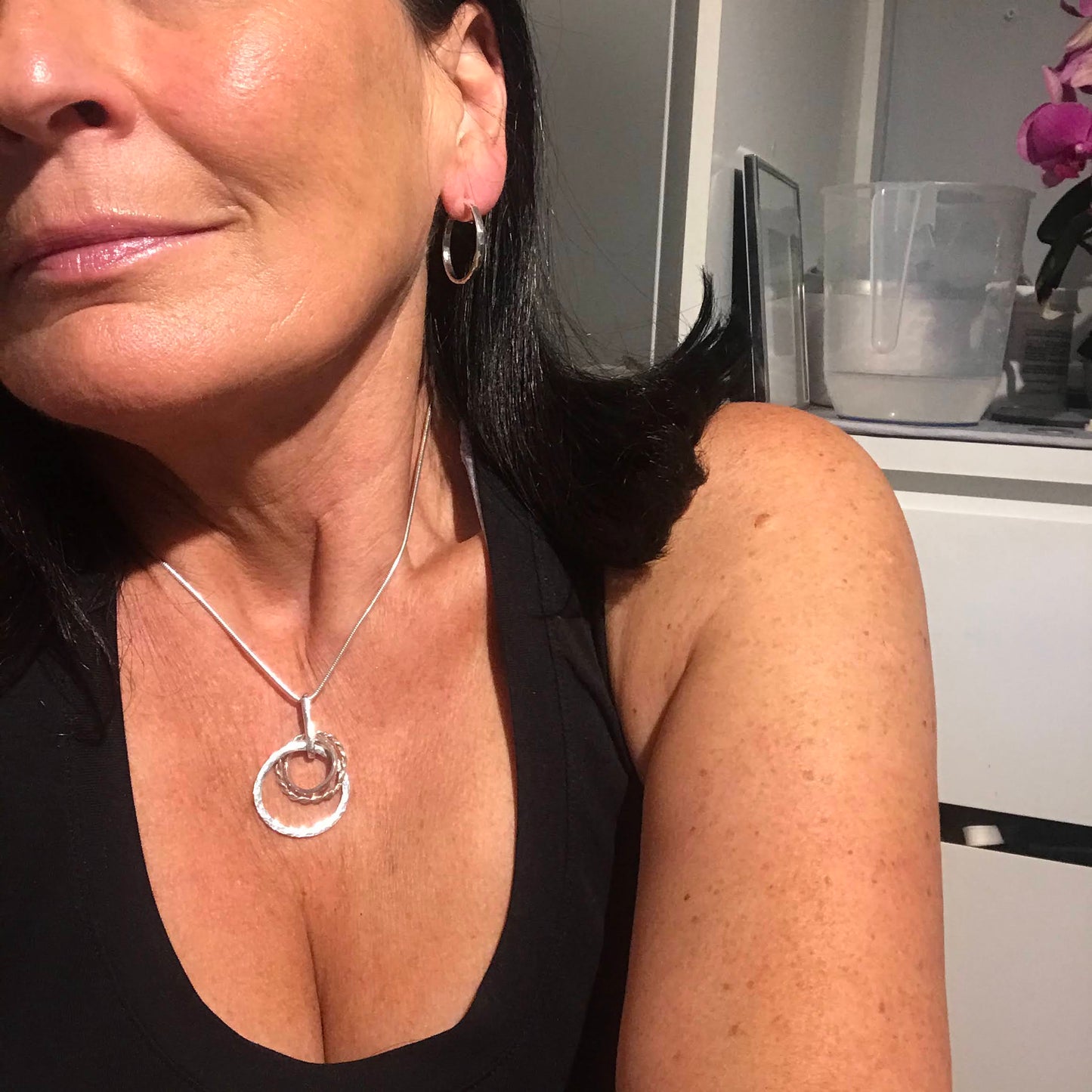 close up sterling silver three loops handmade in Dublin Ireland mode is wearing a black sports top