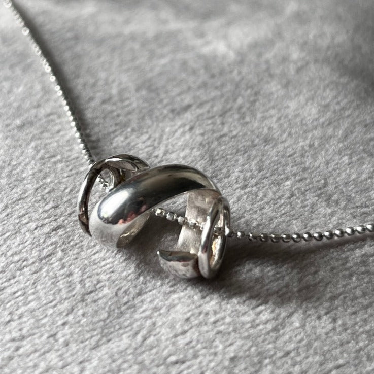 handmade sterling silver pendant necklace with a twisted rolled strip of sterling silver to represent a wave perfect for the swimmer in you life