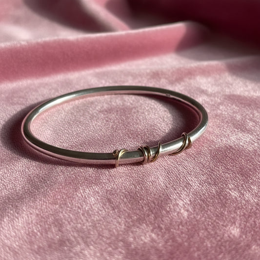 handmade sterling silver solid bangle with 9ct gold wrap of wire twisted around the front of the bangle