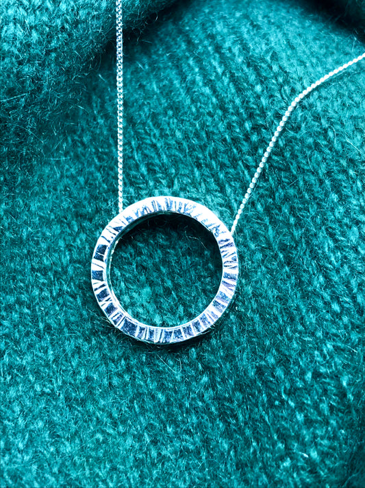 Handmade sterling silver 20cm circle of silver made from 2mm square wire suspended on a hidden bale behind the circle. The circle appears to float on a sterling silver diamond cut curb chain