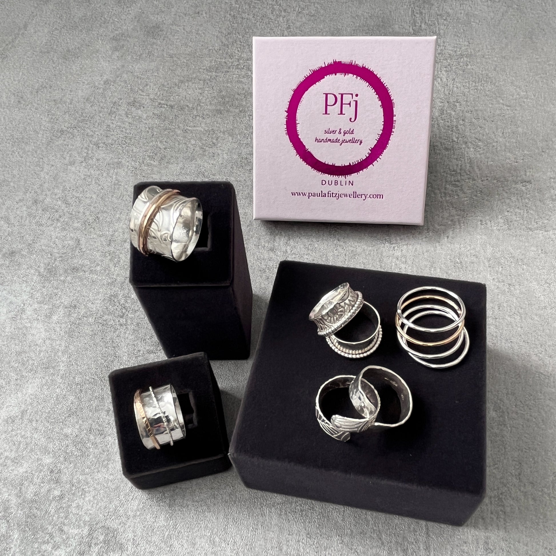 picture of several spinner rings and the pink logoed box that it is presented in when you buy