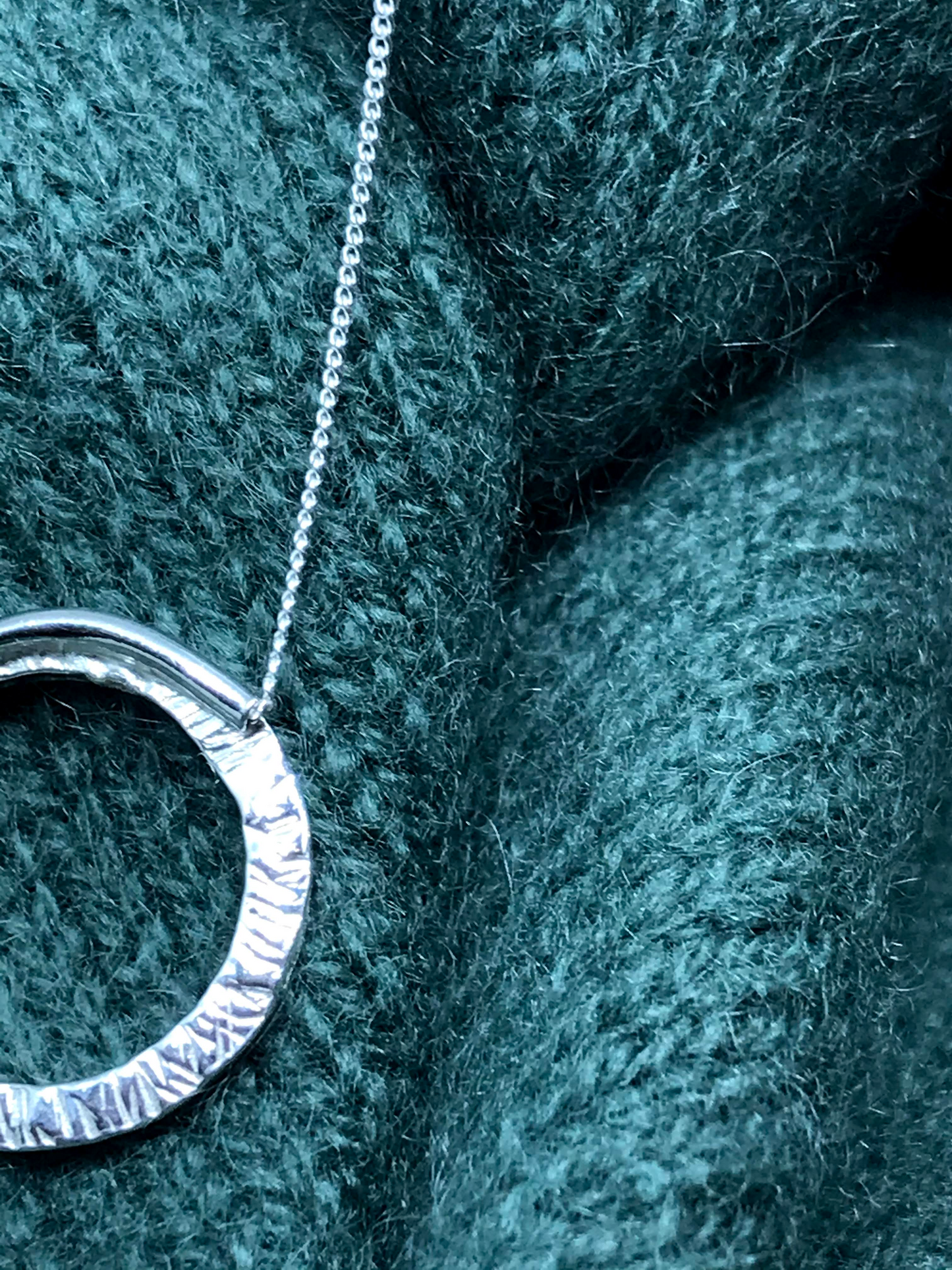 Handmade sterling silver 20cm circle of silver made from 2mm square wire suspended on a hidden bale behind the circle. The circle appears to float on a sterling silver diamond cut curb chain picture shows the back of the circle