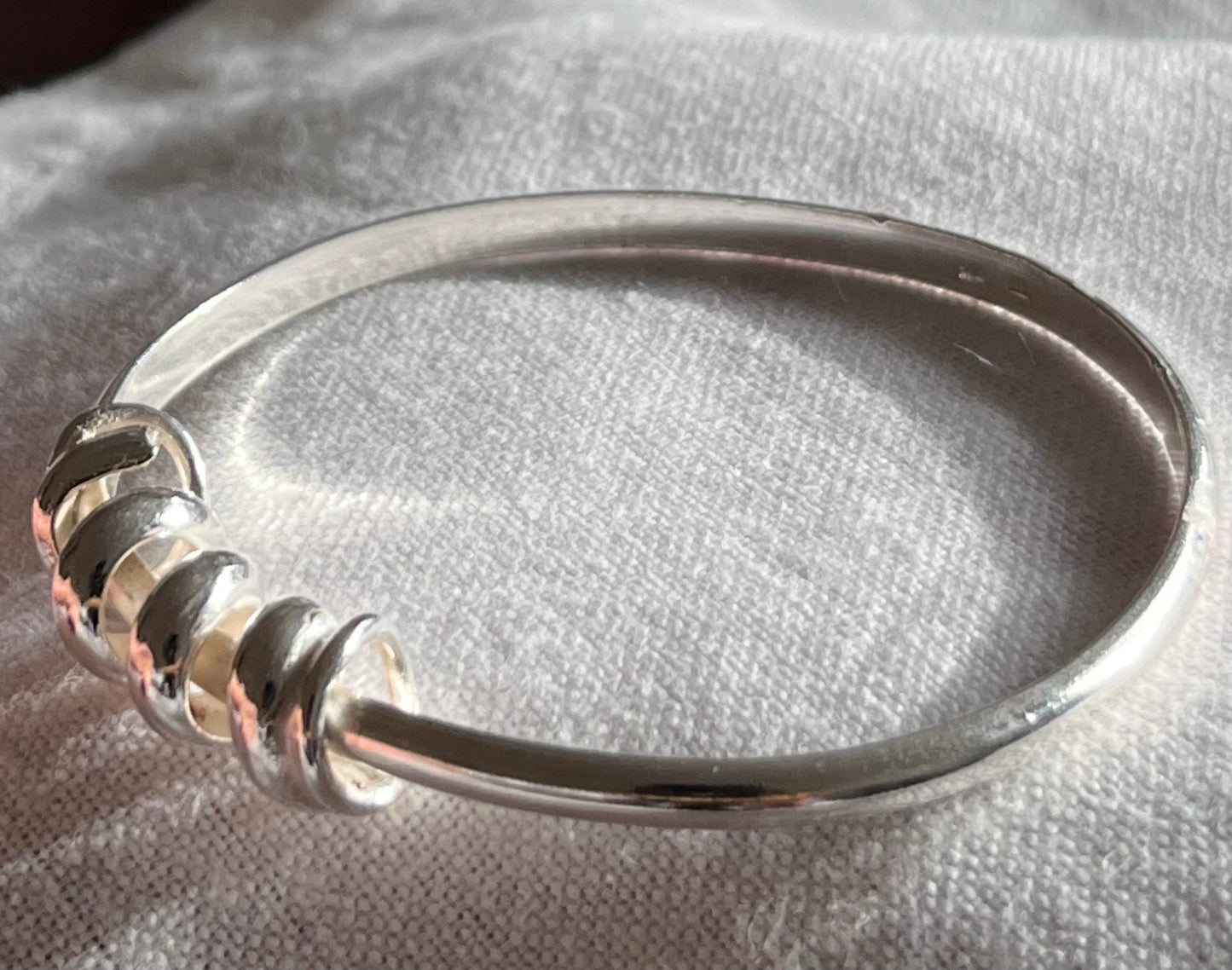 handmade sterling silver bangle. The profile of the silver band is D shaped. with a twisted rolled strip of sterling silver to represent a wave perfect for the swimmer in you life