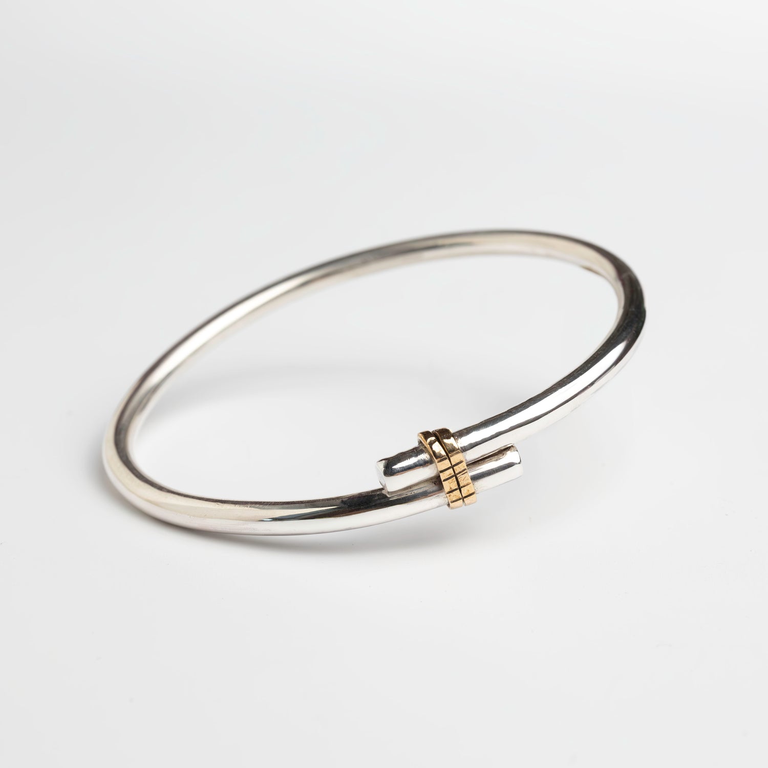 sterling silver bangle with  wrap of gold on the front. The bangle is a piece of silver formed to  a bangle an overlapped at the front with a band of gold filled material