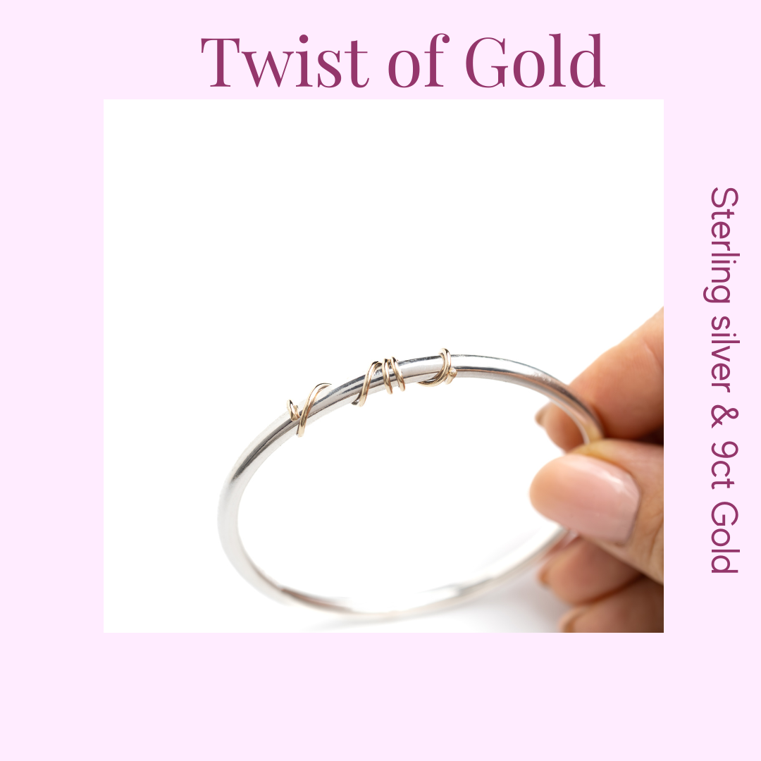 handmade sterling silver solid bangle with 9ct gold wrap of wire twisted around the front of the bangle held here in the models hand