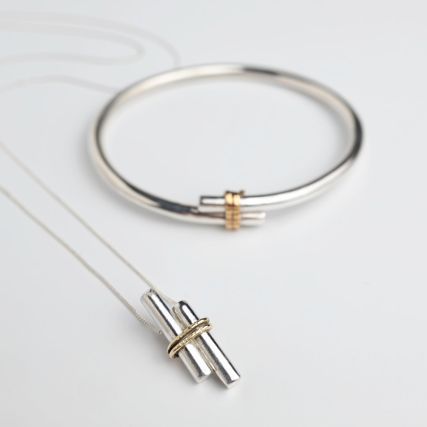 sterling silver solid bangle with gold embellished piece on the front shown here with a matching pendant with magnetic clasp