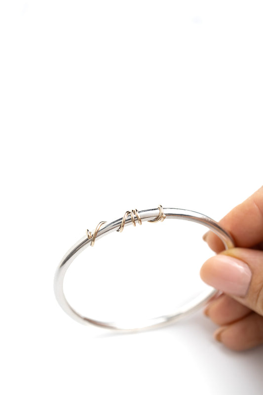 handmade sterling silver solid bangle with 9ct gold wrap of wire twisted around the front of the bangle