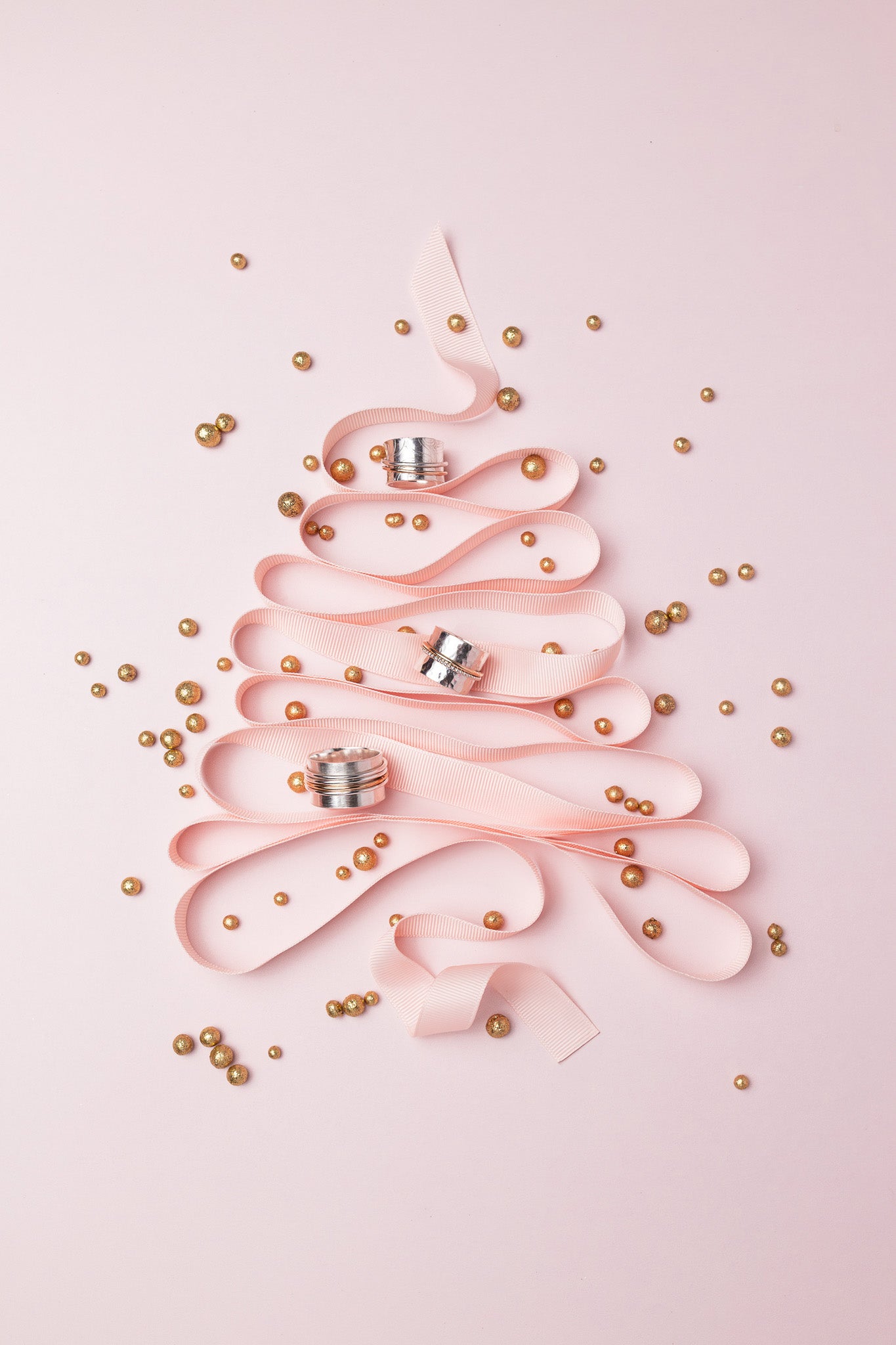pink decorative ribbon in the shape of a christmas tree with gold balls and three spinner rings