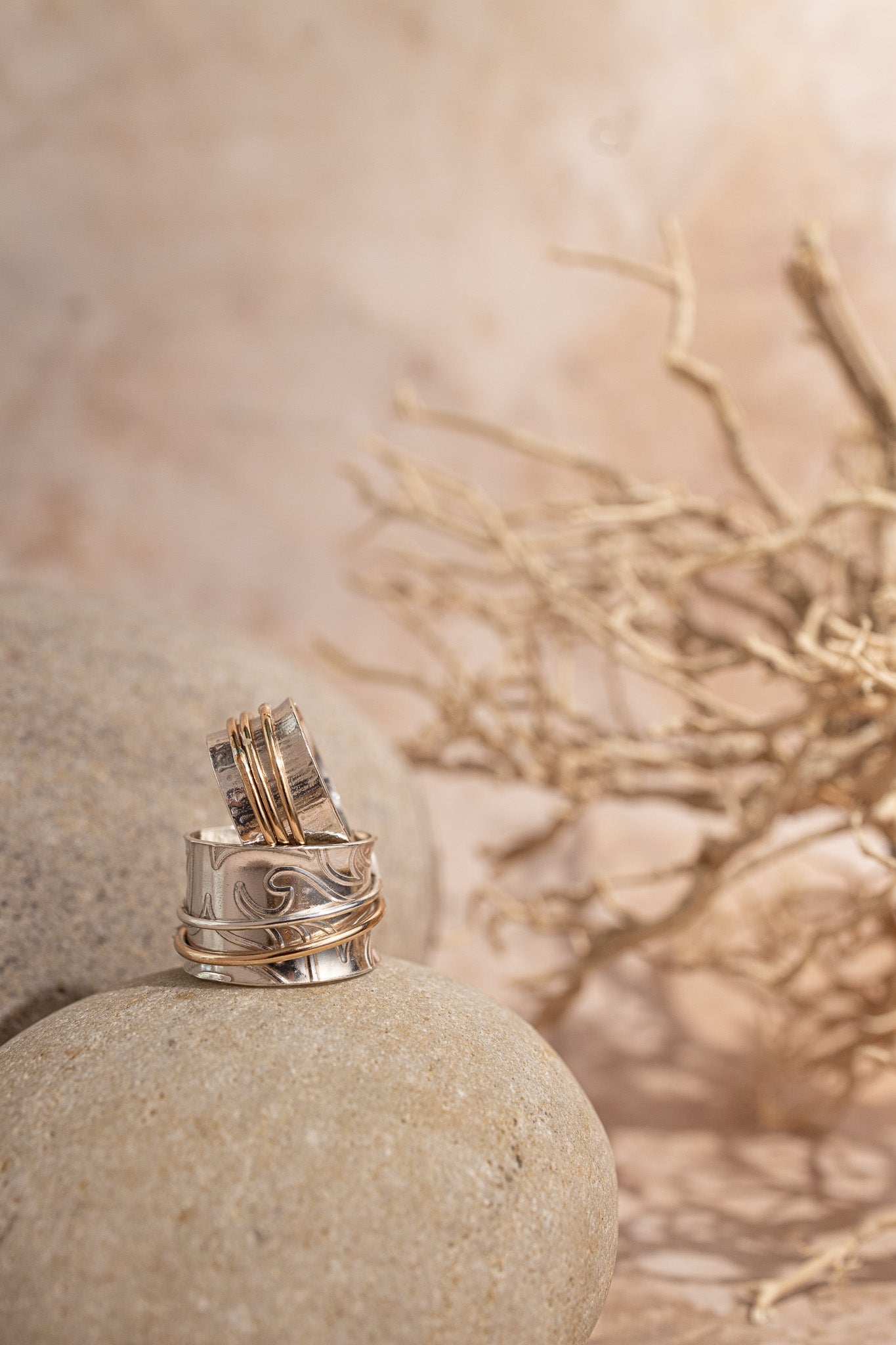two spinner rings standing on a sandstone with a twig in the background 
