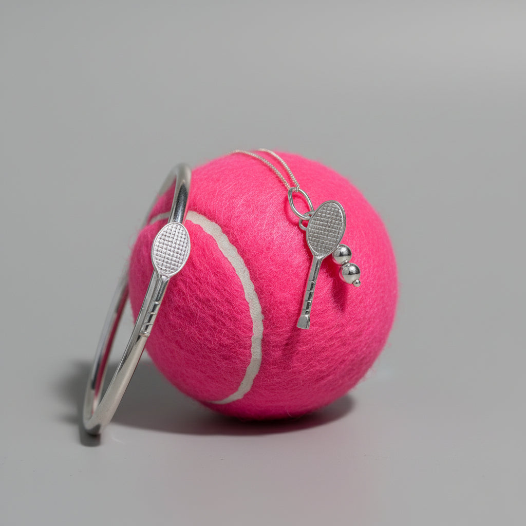 Sterling silver bangle and sterling silver tennis pendant on a green tennis ball with green background