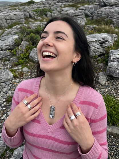 Woman in a pink sweater laughing outdoors with rocky landscape