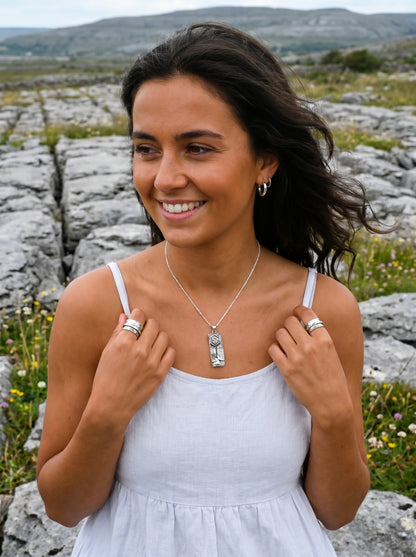 Woman in a white dress with jewelry standing in a rocky landscape