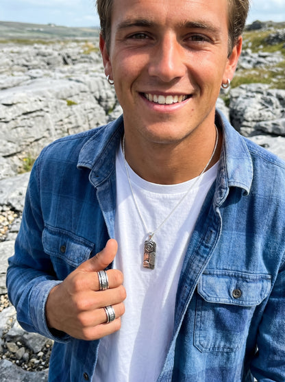 Man giving a thumbs up outdoors with rocky landscape in the background