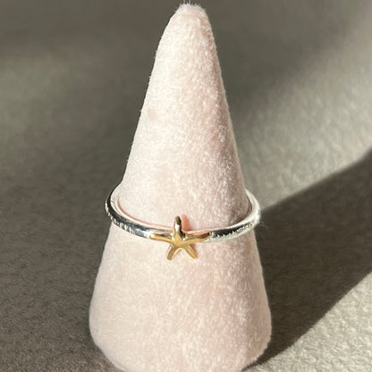 Ring with a star design on a cone-shaped pink stand against a gray background