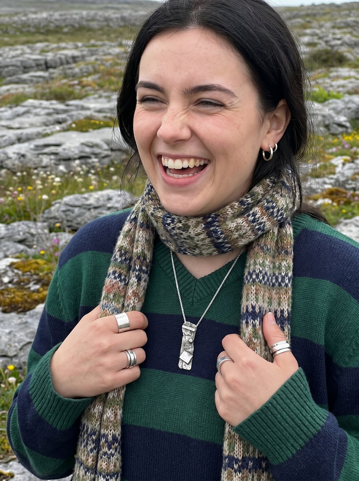 Woman wearing a striped sweater and patterned scarf in a rocky landscape