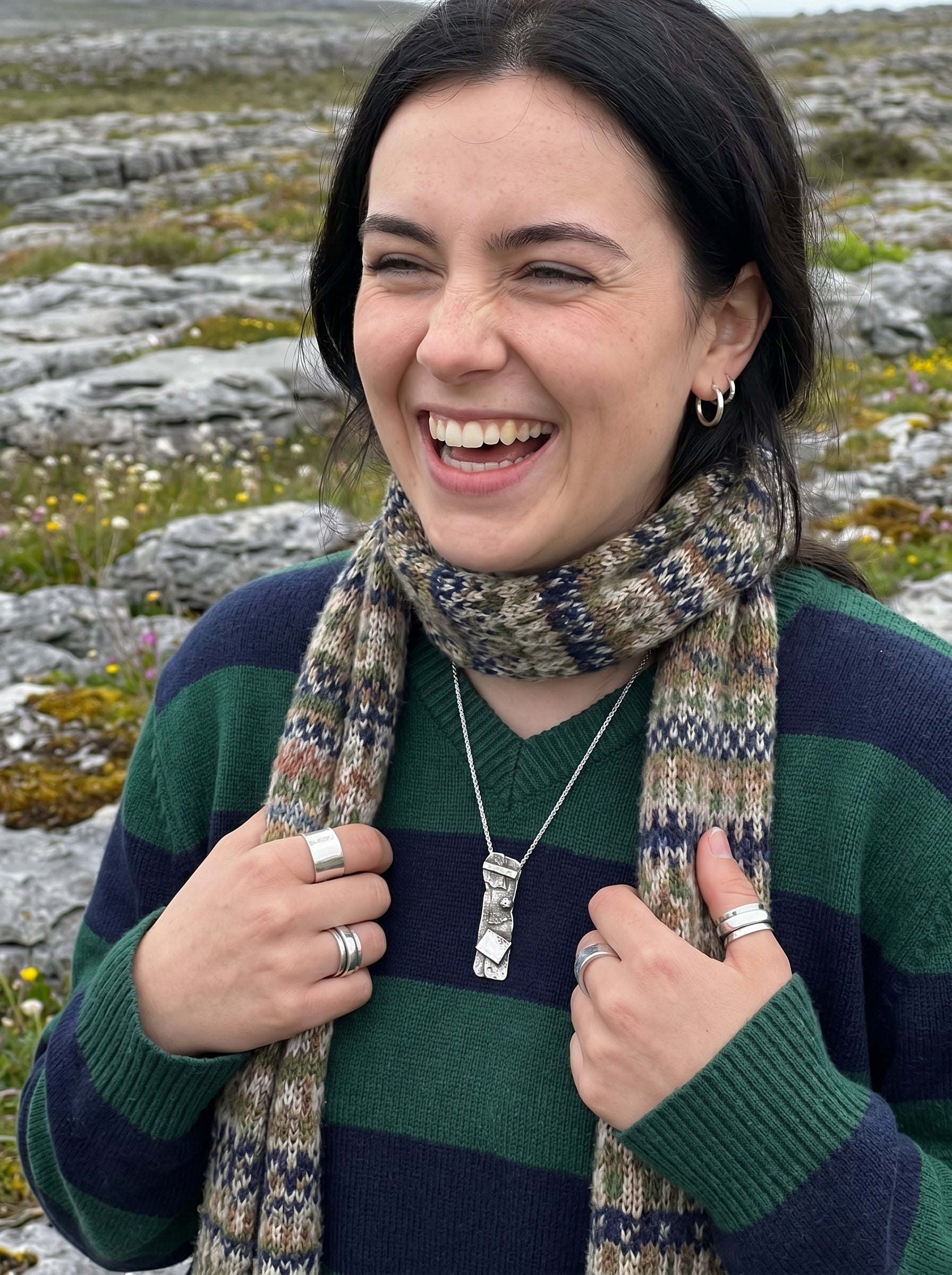 Woman wearing a striped sweater and patterned scarf in a rocky landscape