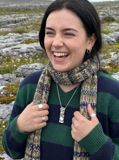 Woman wearing a striped sweater and patterned scarf in a rocky landscape