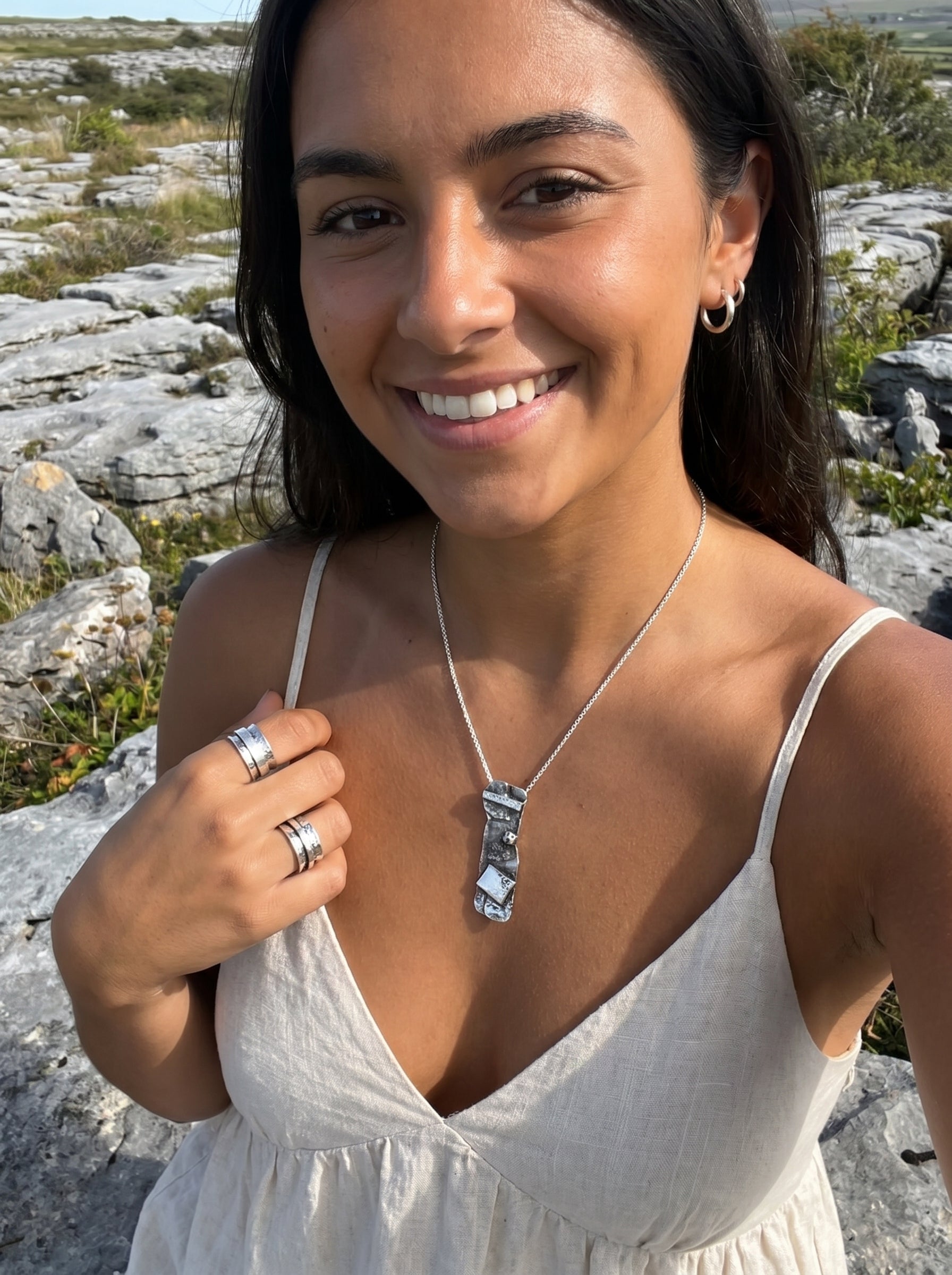 Woman wearing a necklace outdoors with rocky landscape in the background