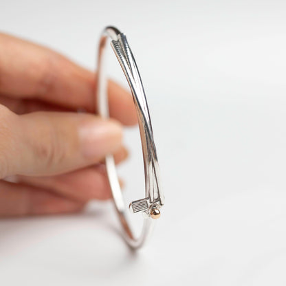 models hand is holding sterling silver handmade solid silver bangle with a golf club and golf ball motif