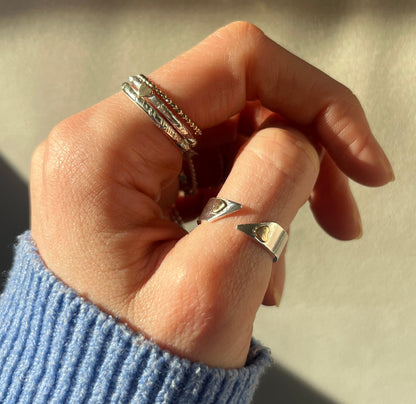 Hand wearing multiple silver rings with a light background