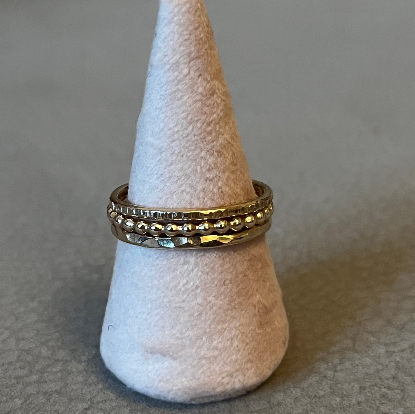 Gold ring on a white cone-shaped stand against a neutral background