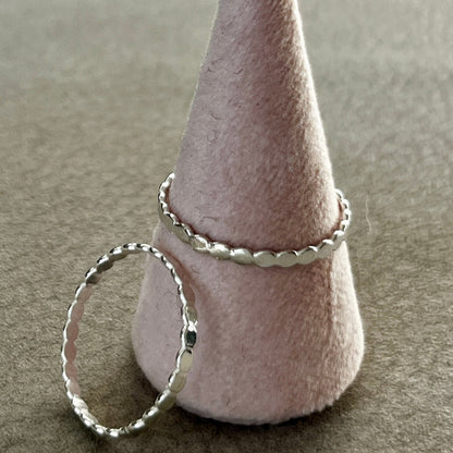 Silver ring on a cone-shaped felt stand against a neutral background