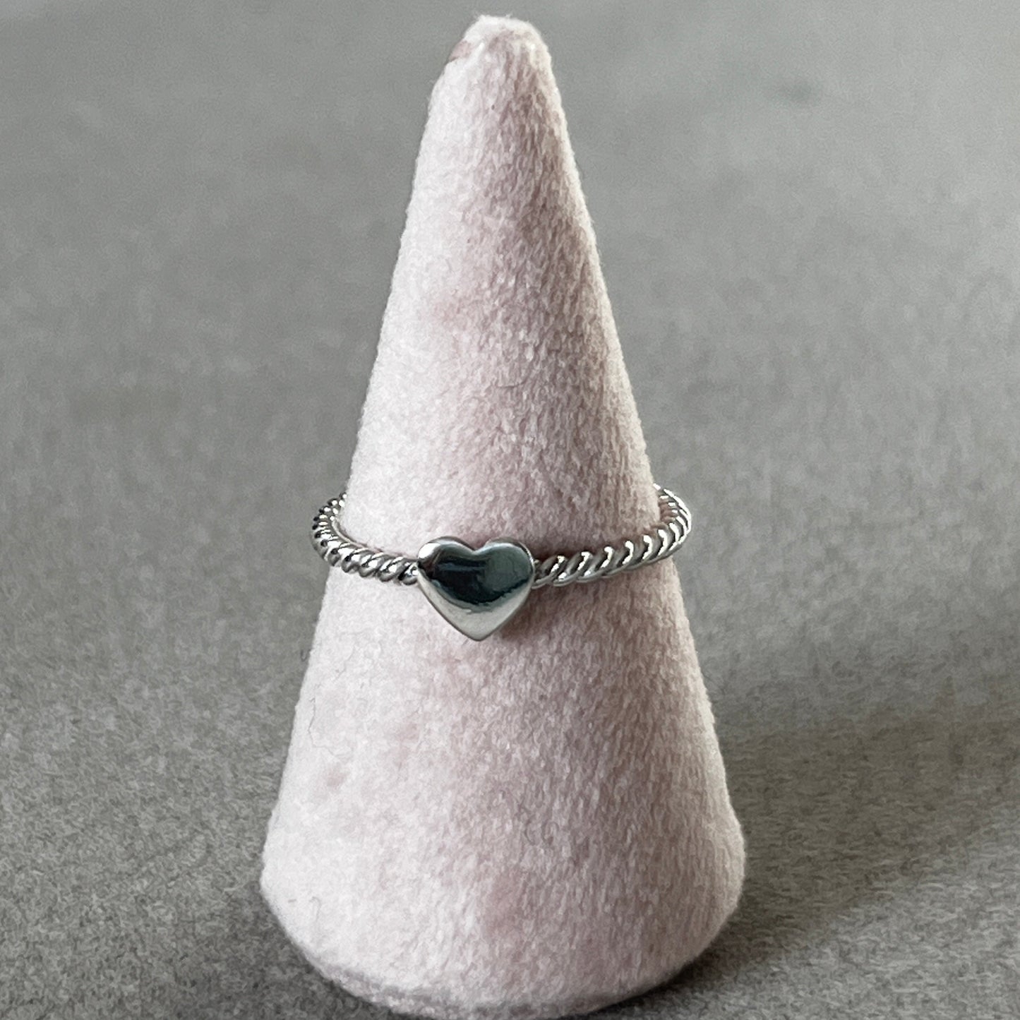 Silver ring with a heart design on a gray surface