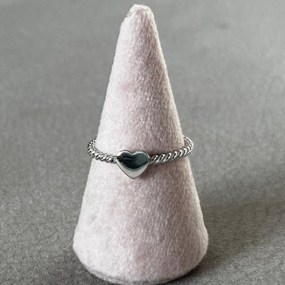 Silver ring with a heart design on a gray surface