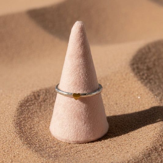 Silver ring with a heart design on a gray surface