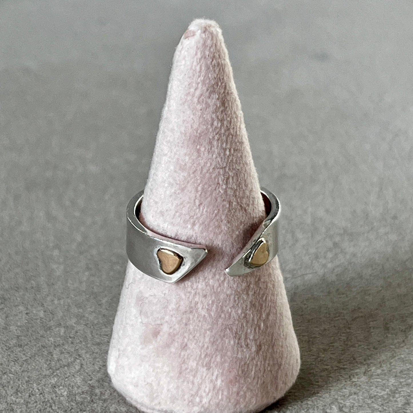 Silver ring with heart-shaped stones on a cone-shaped gray stand.