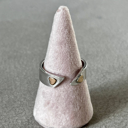 Silver ring with heart-shaped stones on a cone-shaped gray stand.