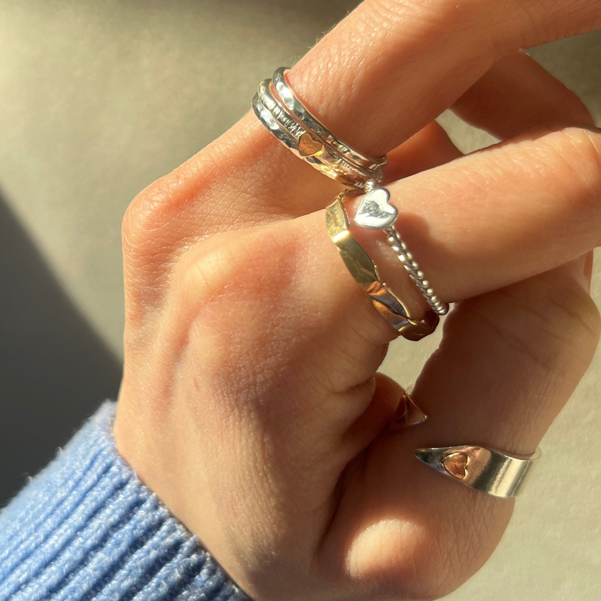 Hand wearing multiple rings with a neutral background