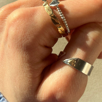 Hand wearing multiple silver rings on a neutral background