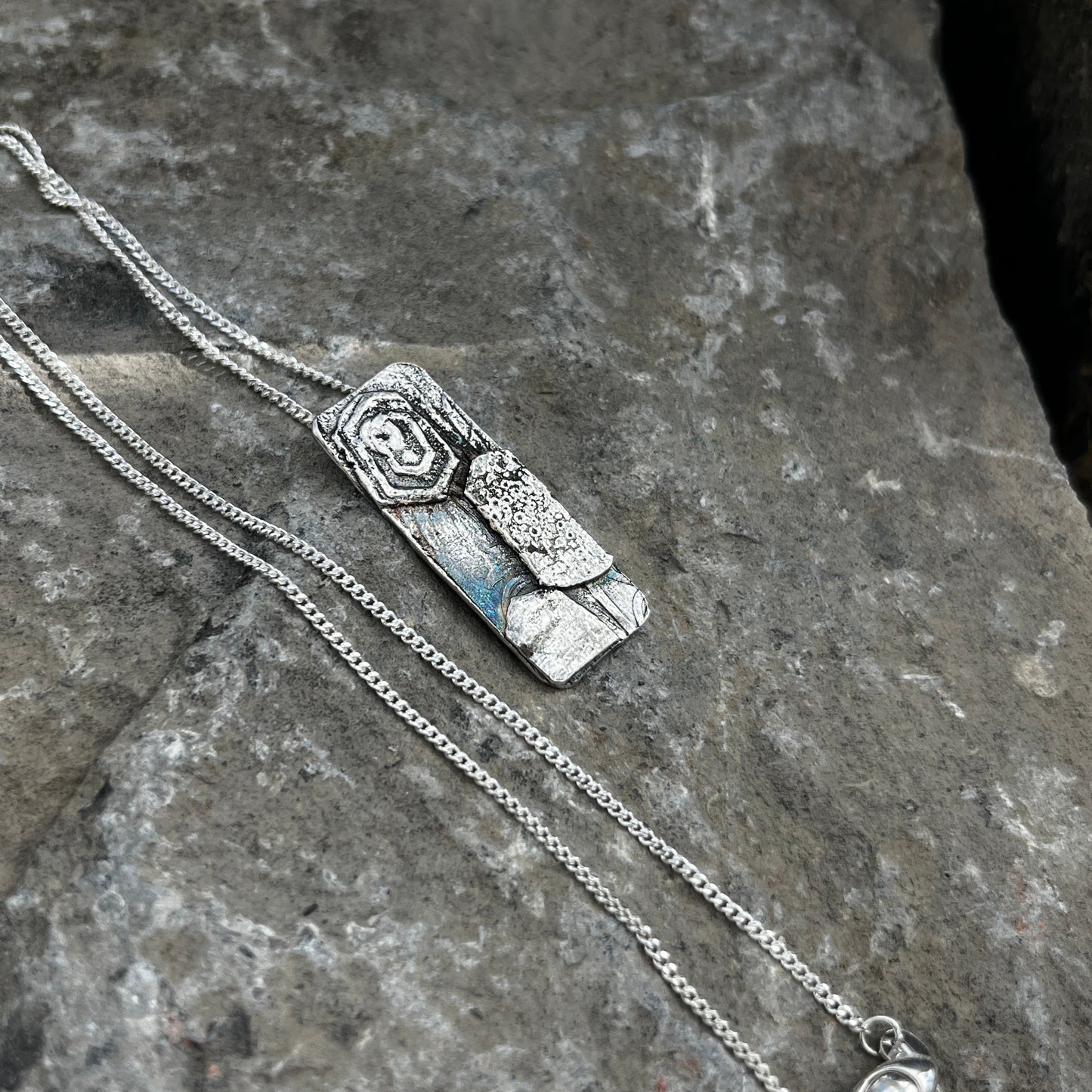 Silver necklace with a pendant on a stone surface
