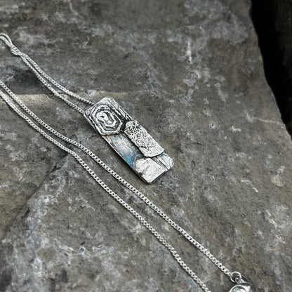Silver necklace with a pendant on a stone surface